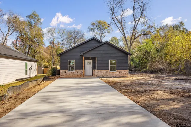 a front view of a house with a garden and trees