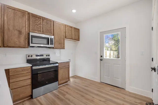 a kitchen with granite countertop wooden cabinets stove top oven and sink