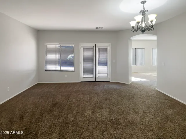 en empty room with windows and chandelier