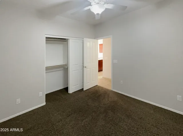 an empty room with a ceiling fan and closet area