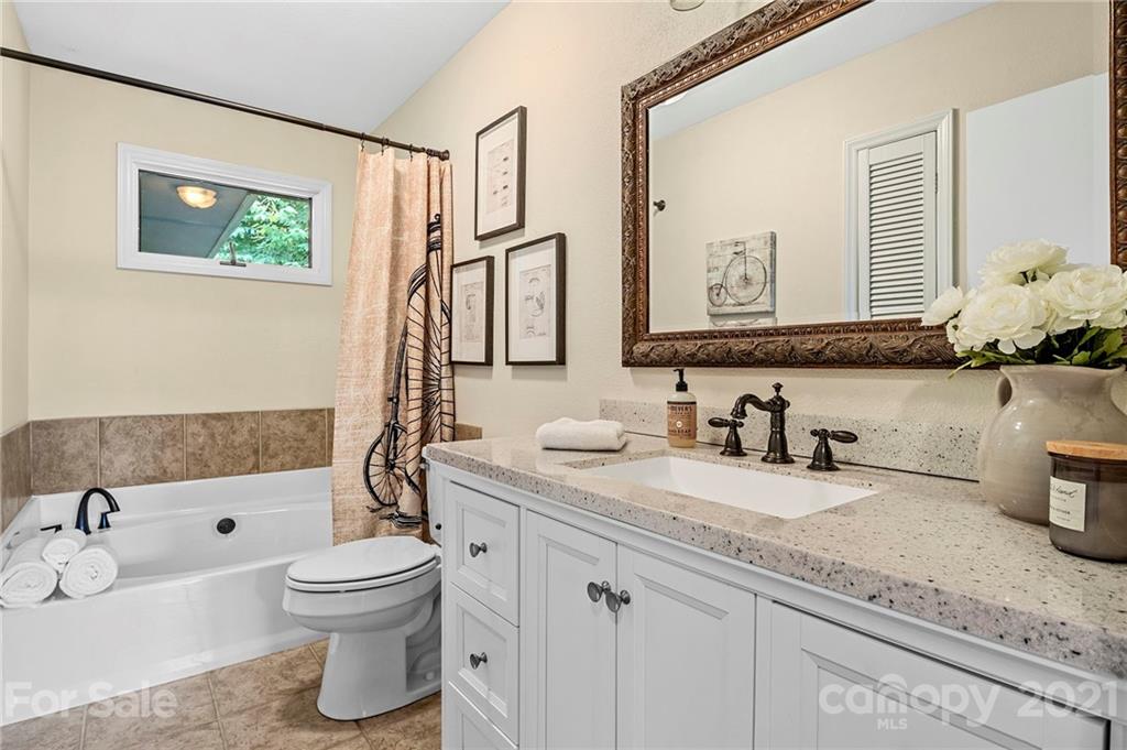 1004 Lickstone Road Waynesville, NC 28786 - Photo 23 of 39 a bathroom with a granite countertop sink mirror vanity bathtub and a toilet