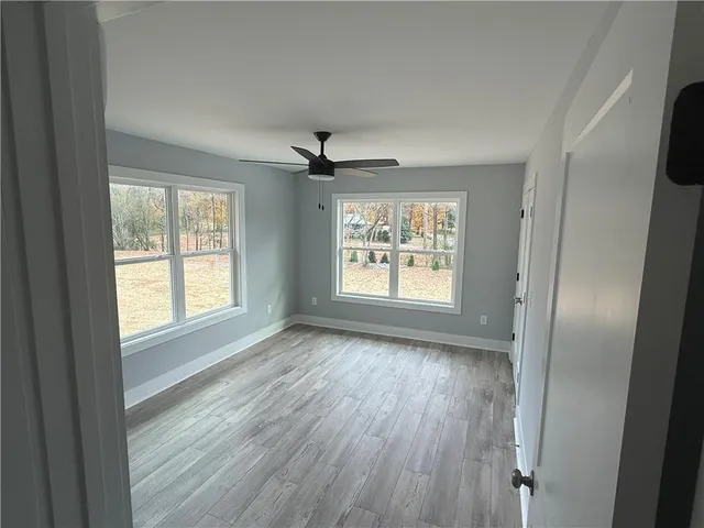 a view of an empty room with a window and wooden floor