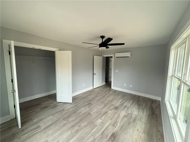 a view of empty room with wooden floor and fan