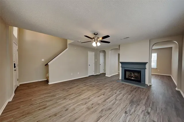 a view of an empty room with wooden floor fireplace and a window
