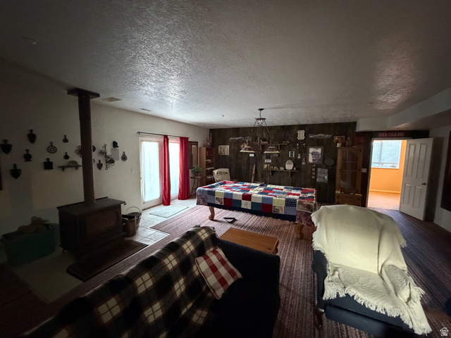10000 North 6730th East Spring City, UT 84662 - Photo 17 of 31 Spacious living area featuring a wood-burning stove, patio door with vertical window panes, and a wood-paneled accent wall