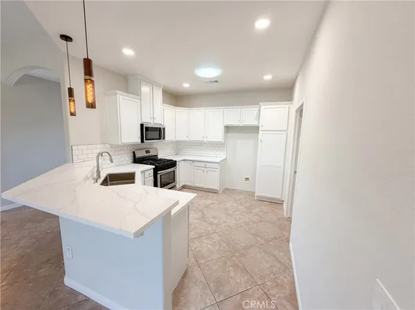 a large kitchen with kitchen island a sink stainless steel appliances and white cabinets
