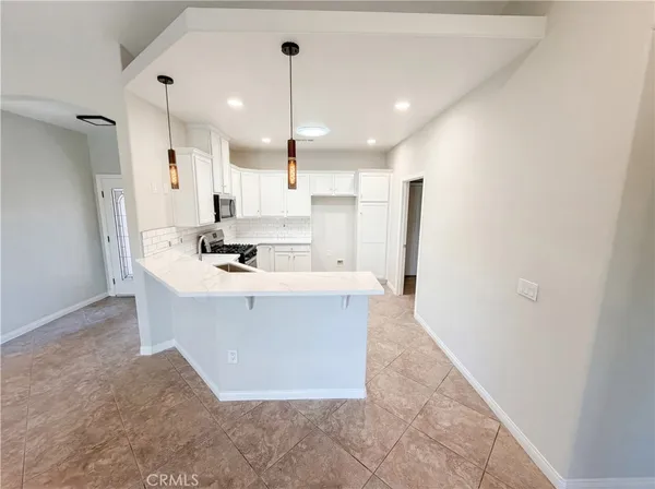 a view of kitchen with stainless steel appliances kitchen island sink stove and refrigerator