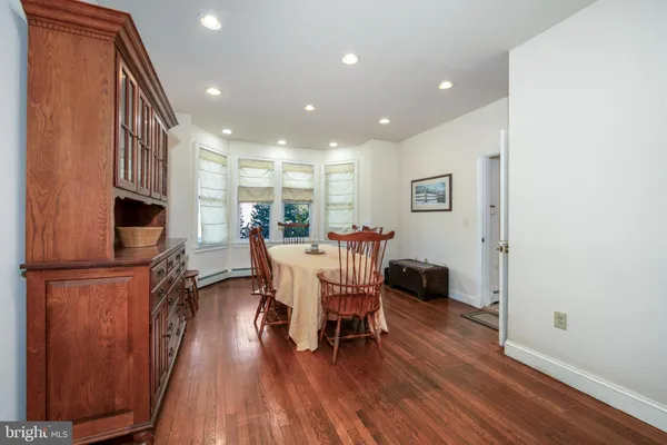 a view of a hallway with wooden floor and a bathroom