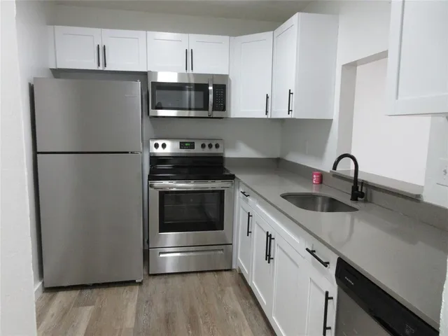 a kitchen with stainless steel appliances a refrigerator stove and white cabinets