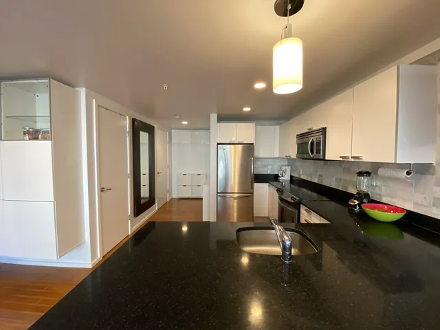 a kitchen with stainless steel appliances kitchen island granite countertop a refrigerator a stove and a sink with granite countertops