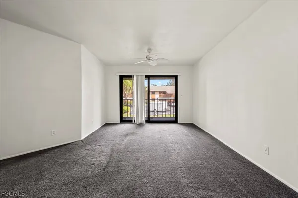an empty room with windows and ceiling fan