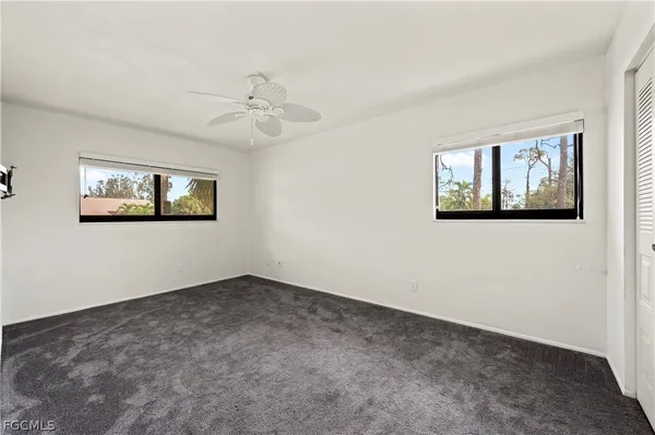 an empty room with windows and ceiling fan