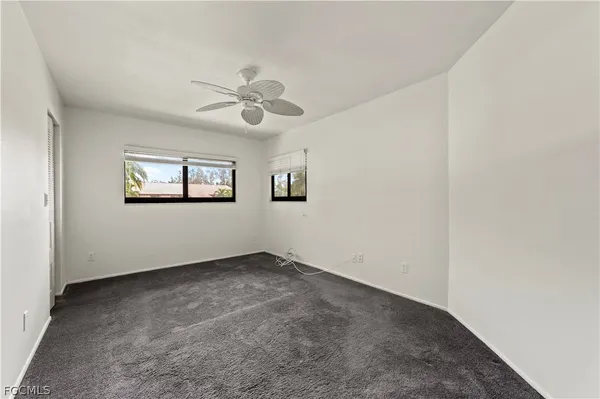 an empty room with a window and a ceiling fan