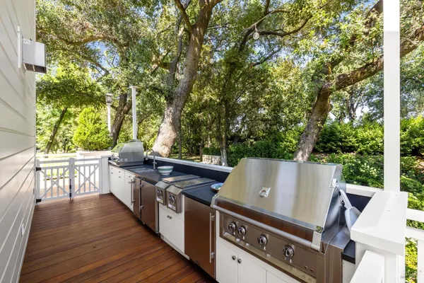 a view of a patio with couches table and chairs with potted plants and big trees