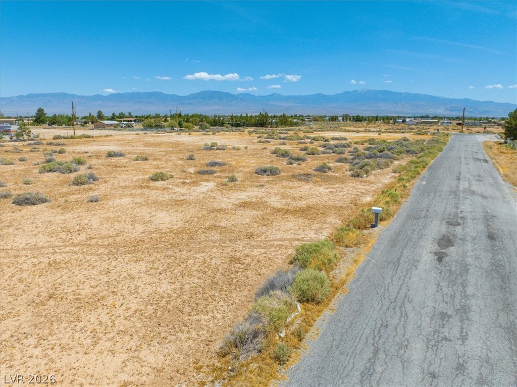 4580 Lawrence Road Pahrump, NV 89048 - Photo 8 of 40 A vast, level lot awaits your vision, framed by distant mountains and a clear sky.