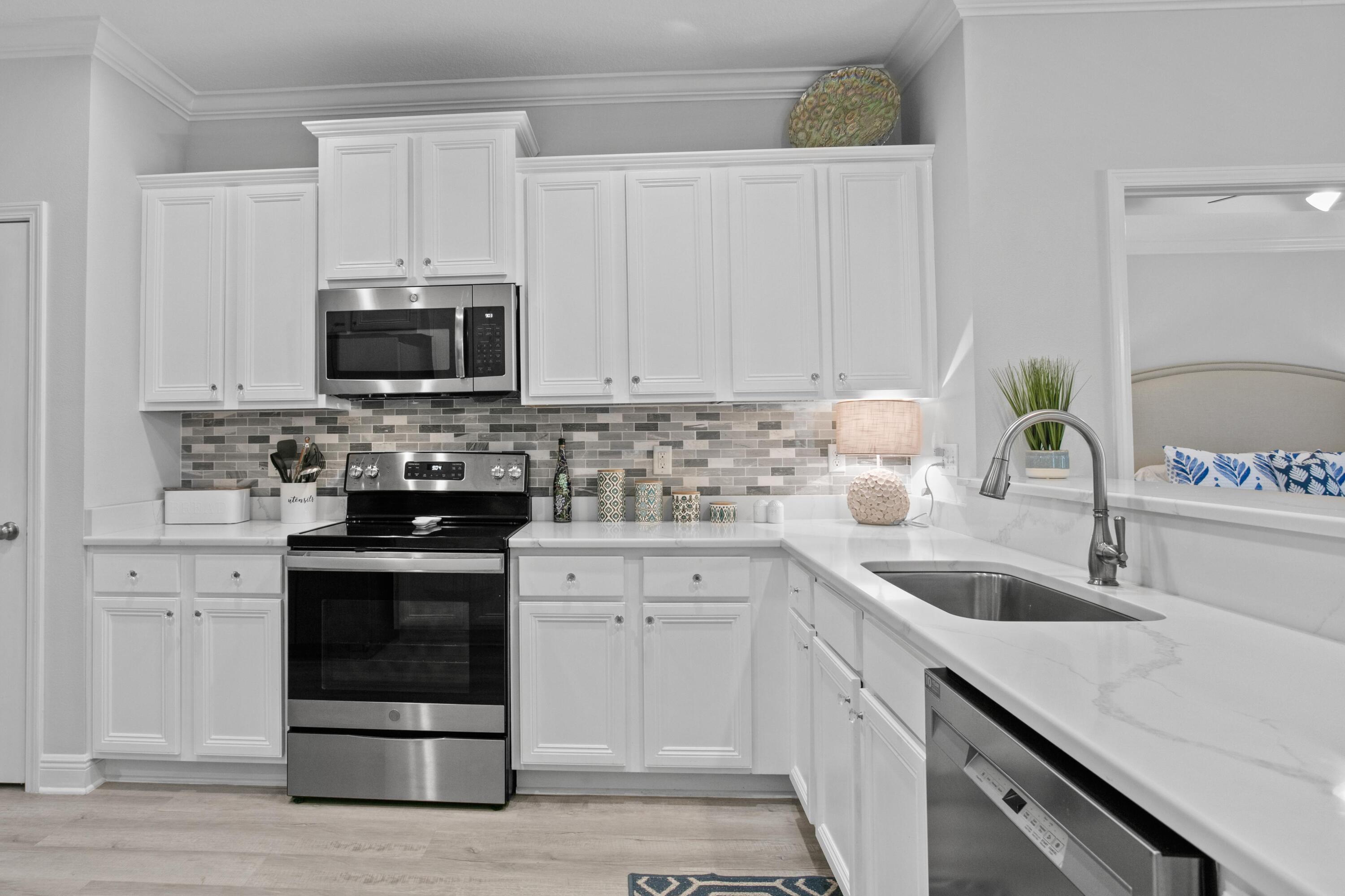 1069 Cocobolo Drive Santa Rosa Beach, FL 32459 - Photo 12 of 46 a kitchen with white cabinets and stainless steel appliances