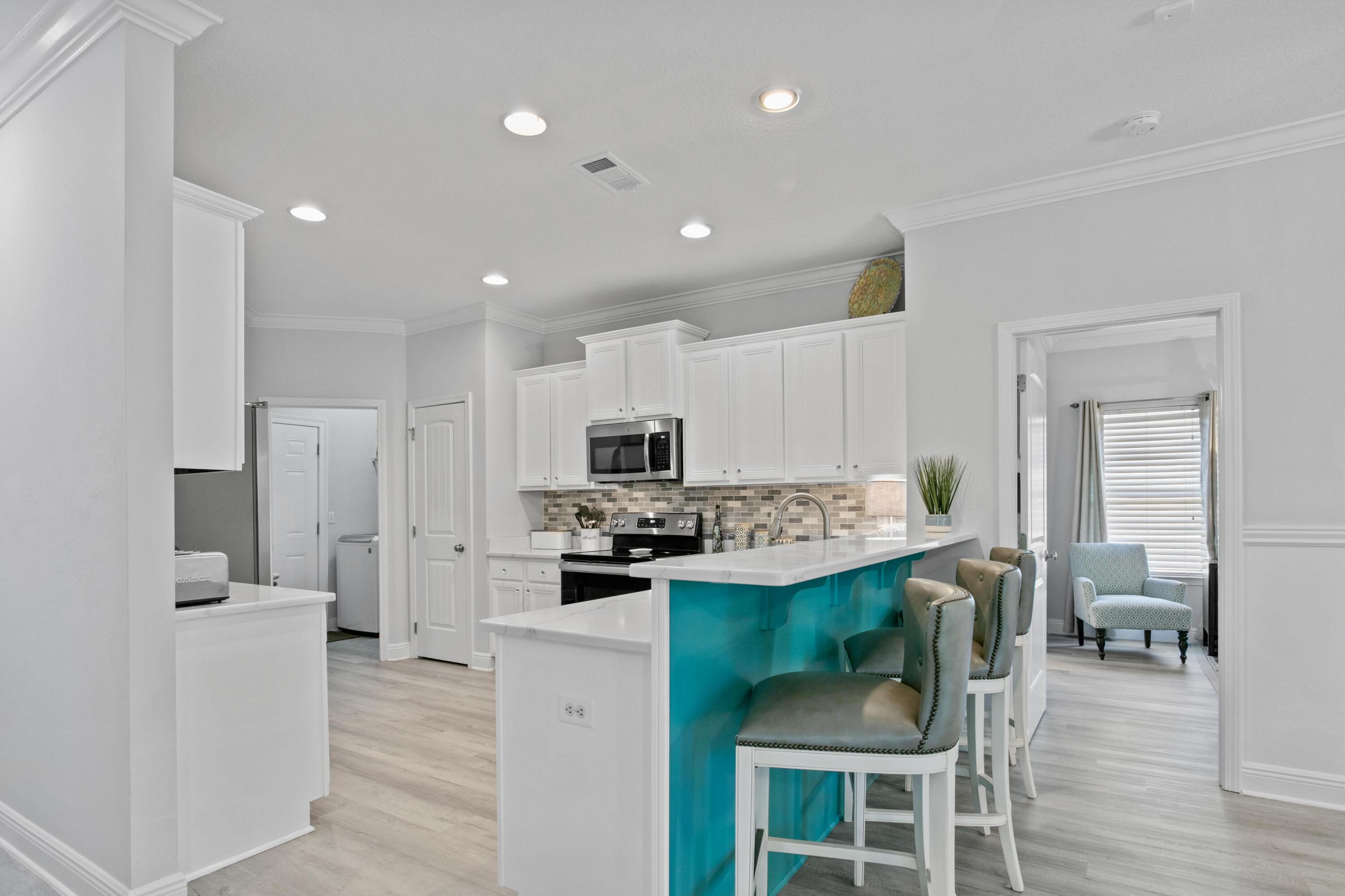 1069 Cocobolo Drive Santa Rosa Beach, FL 32459 - Photo 14 of 46 a kitchen with stainless steel appliances kitchen island granite countertop a refrigerator a stove a sink a dining table and chairs