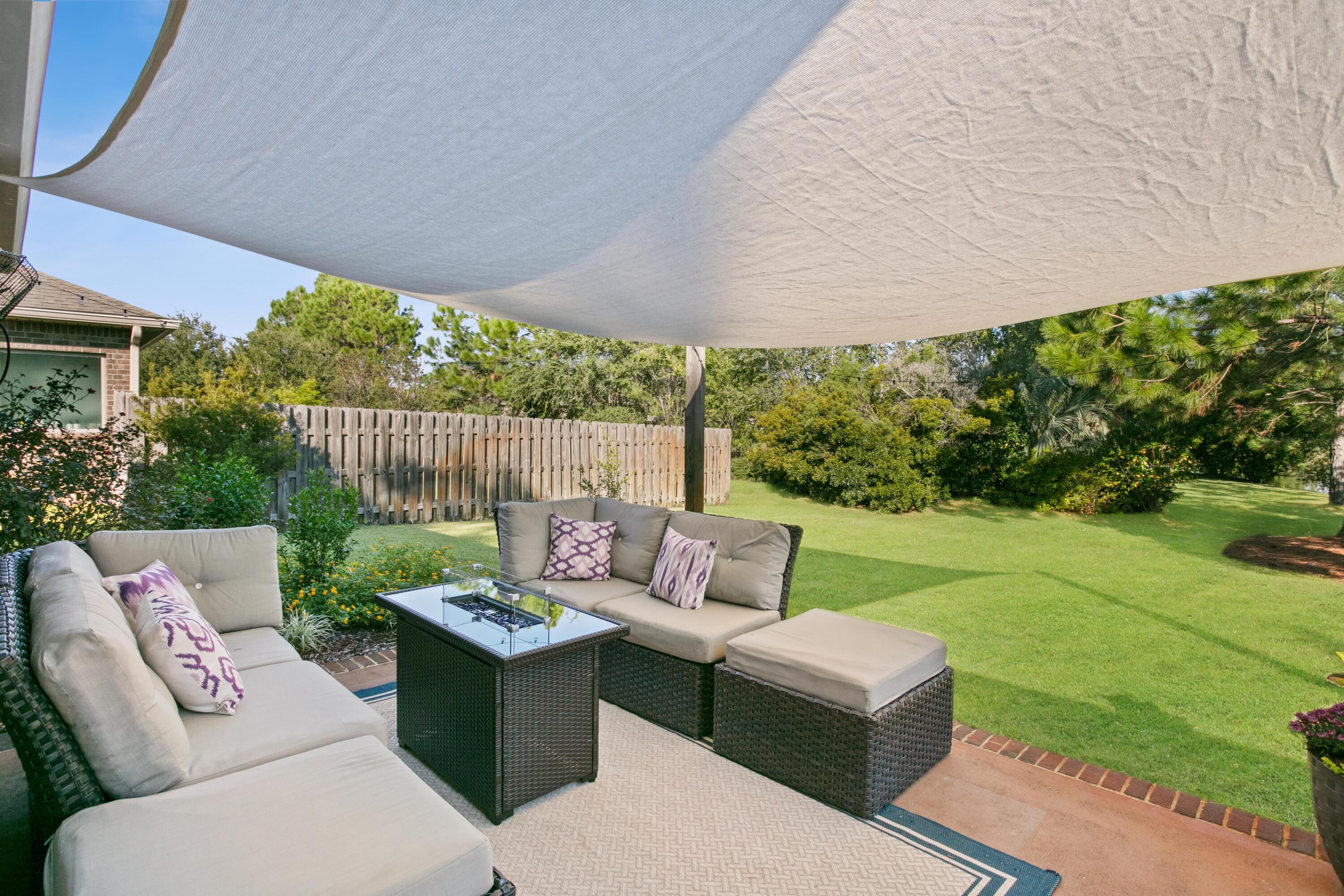 1069 Cocobolo Drive Santa Rosa Beach, FL 32459 - Photo 18 of 46 a view of a patio with couches table and chairs under an umbrella and garden
