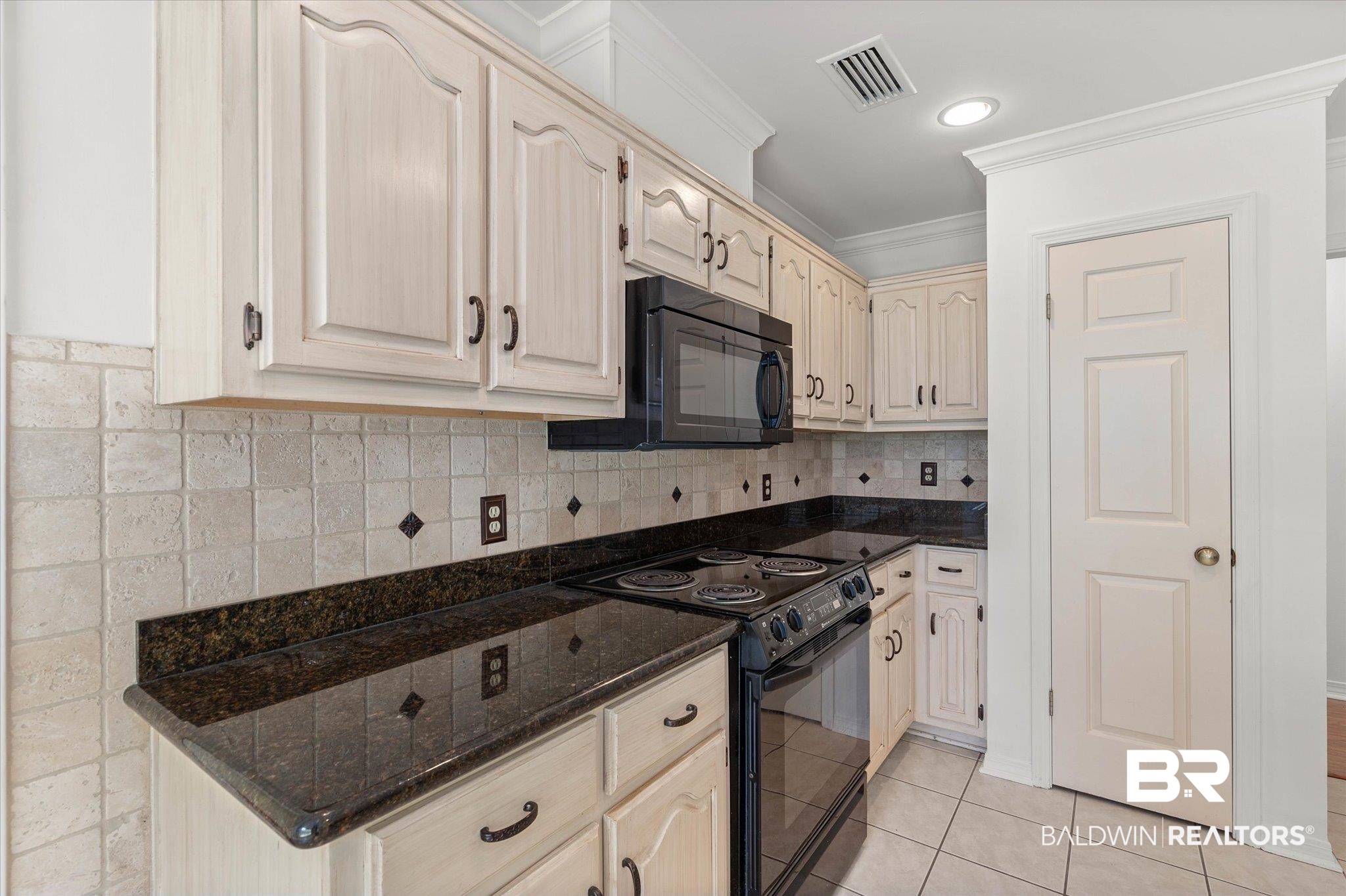 3032 Autumn Ridge Drive West Mobile, AL 36695 - Photo 6 of 20 Kitchen with black appliances, dark stone countertops, ornamental molding, light tile patterned floors, and tasteful backsplash