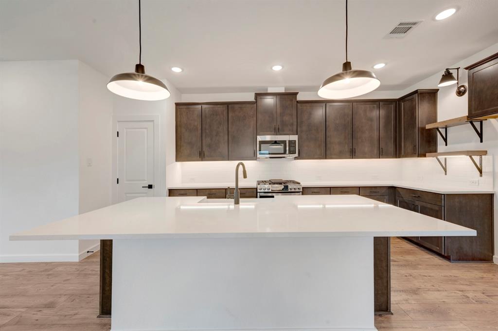 536 Brookside Drive Van Alstyne, TX 75495 - Photo 8 of 30 a large kitchen with kitchen island a large counter top a sink and a stove