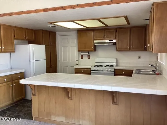 a kitchen with stainless steel appliances a sink a stove a refrigerator white cabinets and wooden floor