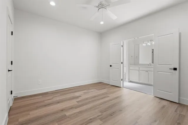 an empty room with wooden floor closet and windows