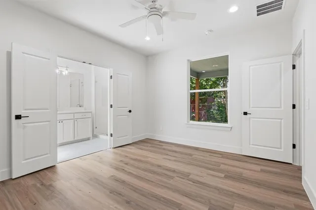 an empty room with wooden floor cabinet and windows