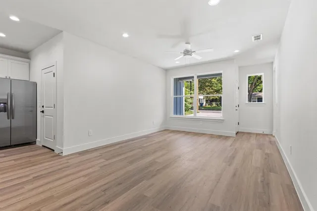 an empty room with wooden floor cabinet and windows