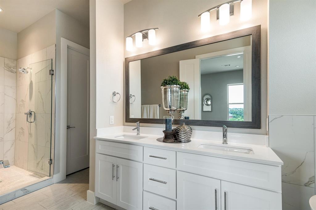 770 North Plano Road, Unit 303 Richardson, TX 75081 - Photo 14 of 25 Well-appointed bathroom featuring a double vanity with white cabinetry and chrome fixtures, a large framed mirror, and a spacious walk-in shower with glass enclosure and marble-look tile