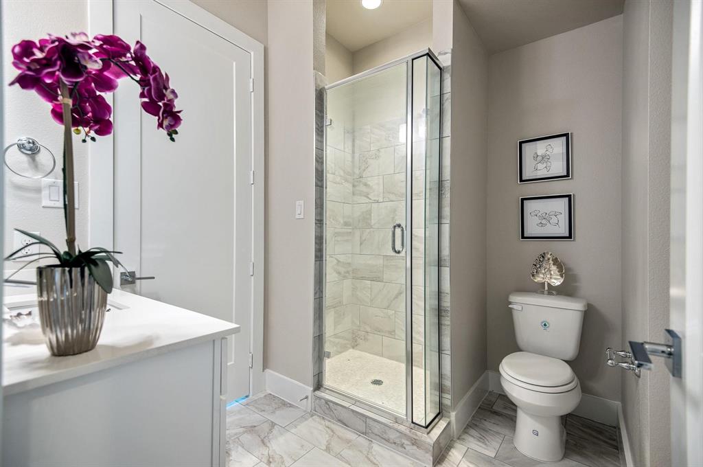 770 North Plano Road, Unit 303 Richardson, TX 75081 - Photo 18 of 25 Bathroom featuring a glass-enclosed shower with tiled walls, a white vanity with a light-colored countertop, and a white toilet