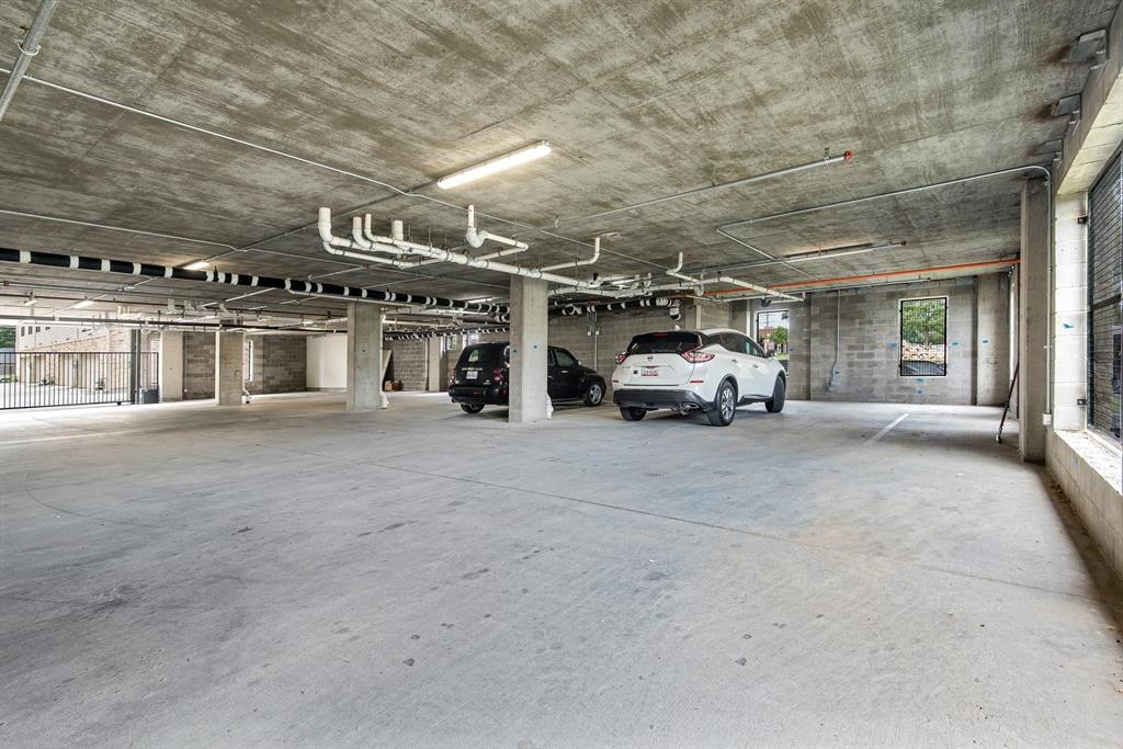 770 North Plano Road, Unit 303 Richardson, TX 75081 - Photo 21 of 25 The property features a concrete parking garage with overhead lighting and exposed piping