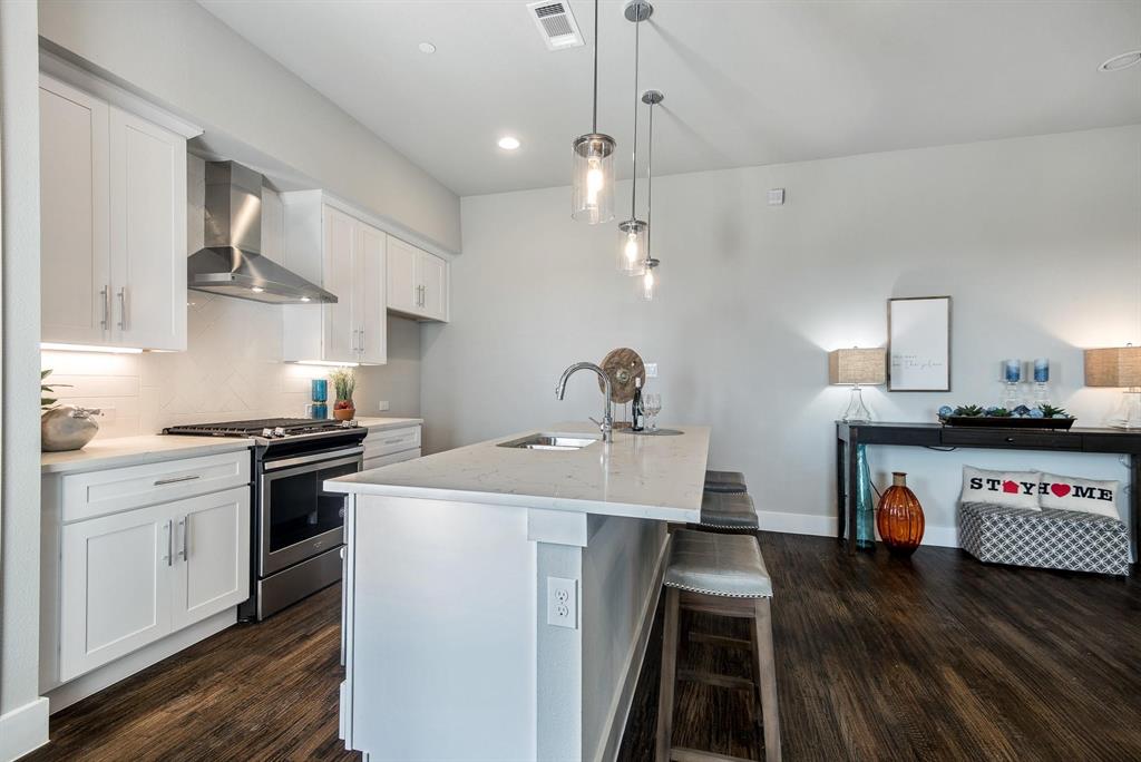 770 North Plano Road, Unit 303 Richardson, TX 75081 - Photo 8 of 25 The property features a kitchen with white cabinetry, stainless steel appliances, and a central island with a sink and seating