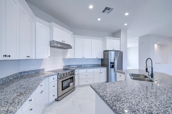 a kitchen with stainless steel appliances granite countertop a sink refrigerator and cabinets