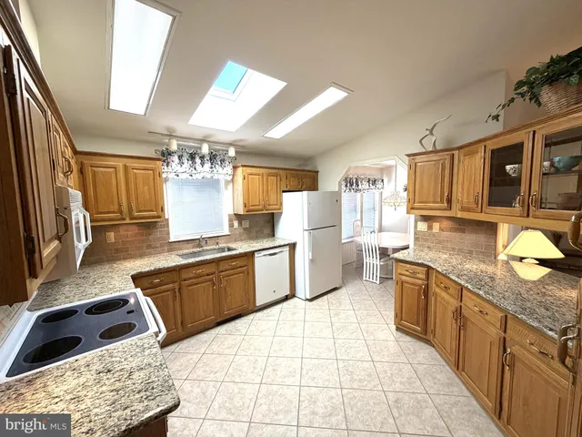 a large kitchen with stainless steel appliances kitchen island granite countertop a sink and cabinets