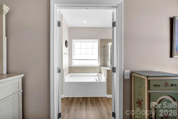 a view of a hallway with wooden floor and a bathroom
