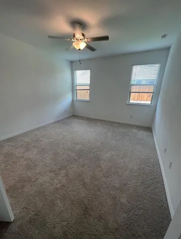 en empty room with windows and chandelier fan
