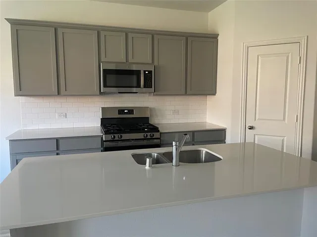 a kitchen with stainless steel appliances granite countertop a sink a stove and a microwave