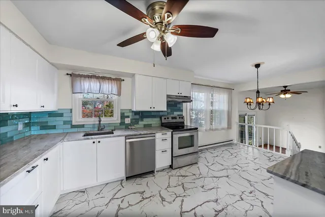 a kitchen with stainless steel appliances a sink a stove a refrigerator cabinets and chairs