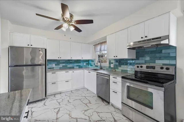 a kitchen with granite countertop a refrigerator stove top oven and cabinets
