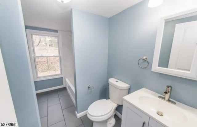 a bathroom with a toilet a sink a mirror and a window