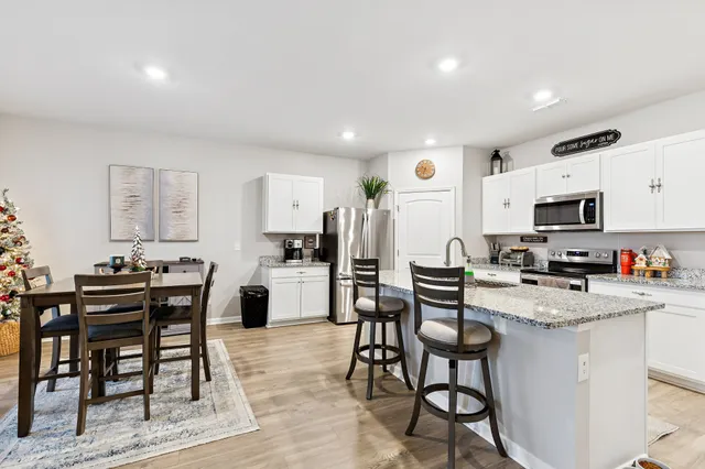 a kitchen with stainless steel appliances a table and chairs in it