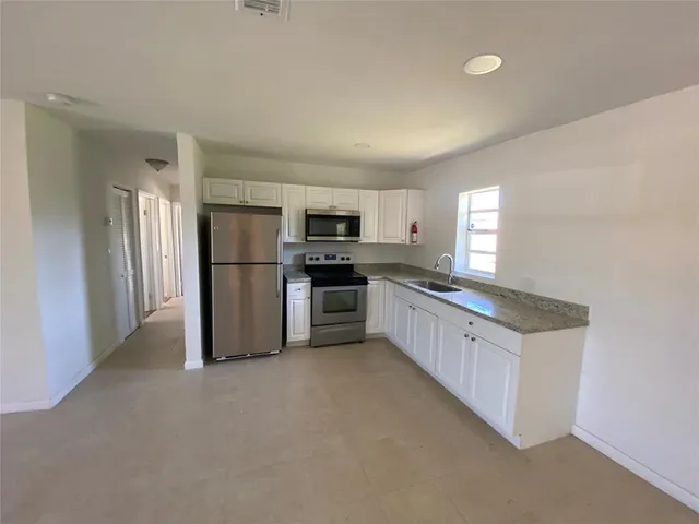 a kitchen with stainless steel appliances a refrigerator a stove a microwave and white cabinets