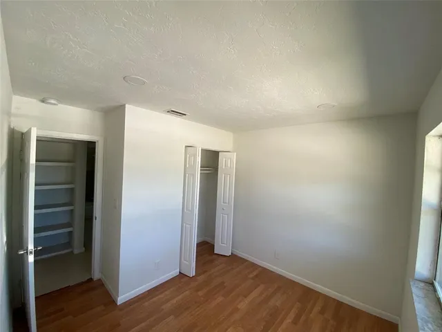 an empty room with wooden floor & closet area