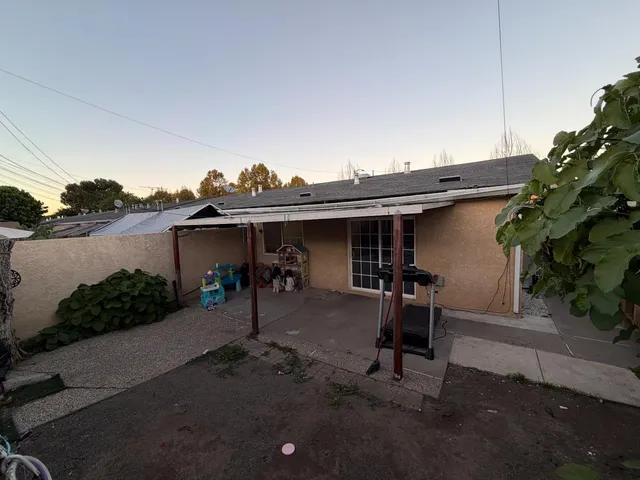 a view of a backyard with table and chairs potted plants and wooden fence