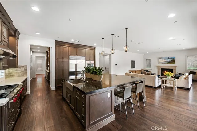 a kitchen with stainless steel appliances a dining table chairs stove refrigerator and cabinets