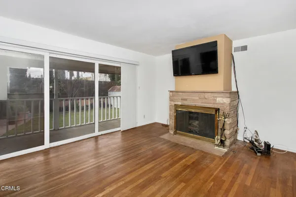 a view of a livingroom with wooden floor and a fireplace