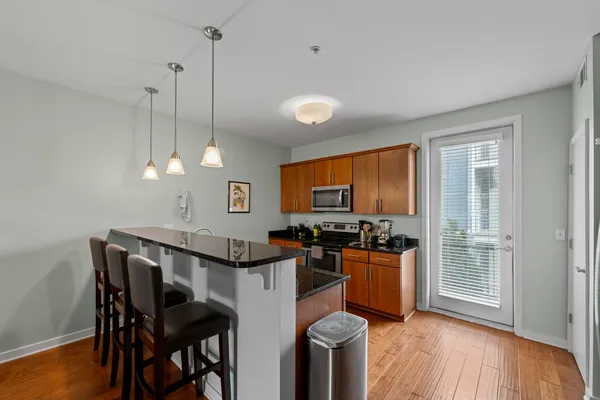 a kitchen with stainless steel appliances granite countertop a stove a refrigerator a sink a dining table and chairs with wooden floor