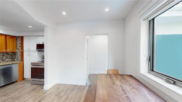 an empty room with wooden floor cabinet and windows