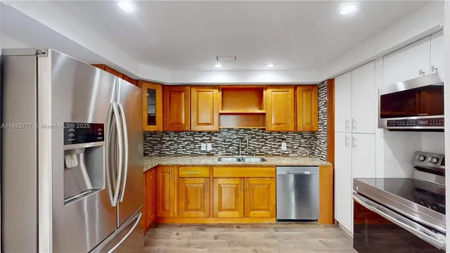 a kitchen with stainless steel appliances granite countertop a refrigerator a stove and a sink