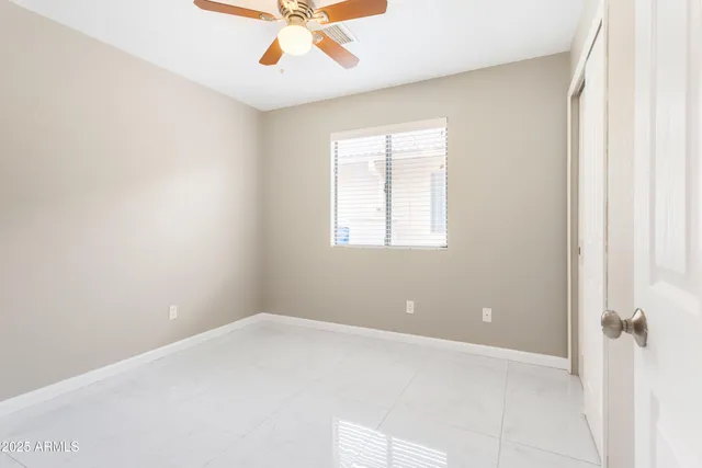 an empty room with a window and a chandelier fan
